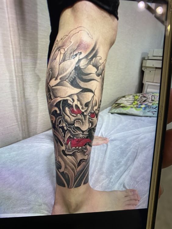 tattoo mặt quỷ mắt đỏ ở bắp chân