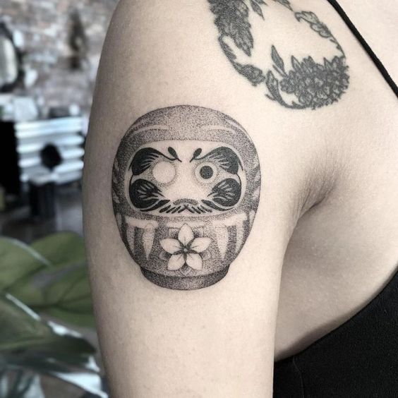 hình xăm mặt tròn cho daruma siêu đáng yêu ở bắp tay cho chị khách